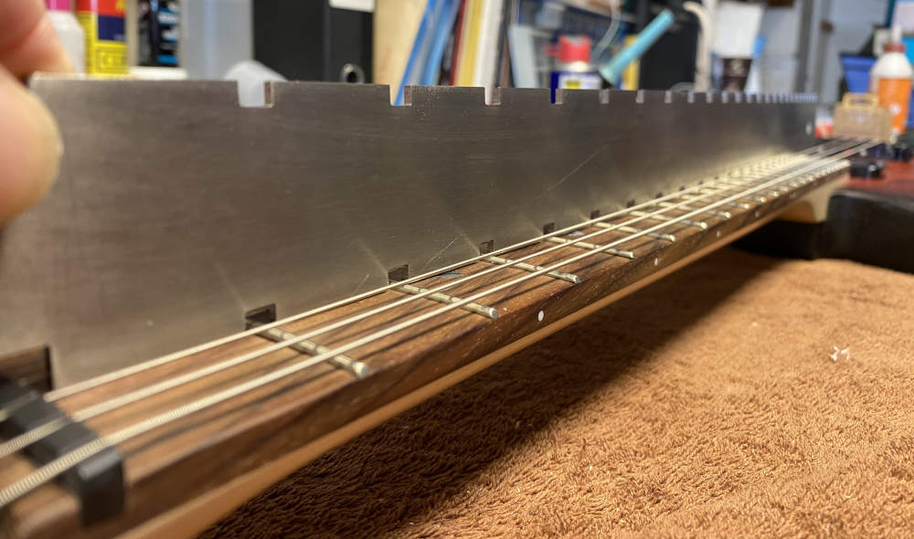 Setting the relief on a guitar neck with a notched straight edge